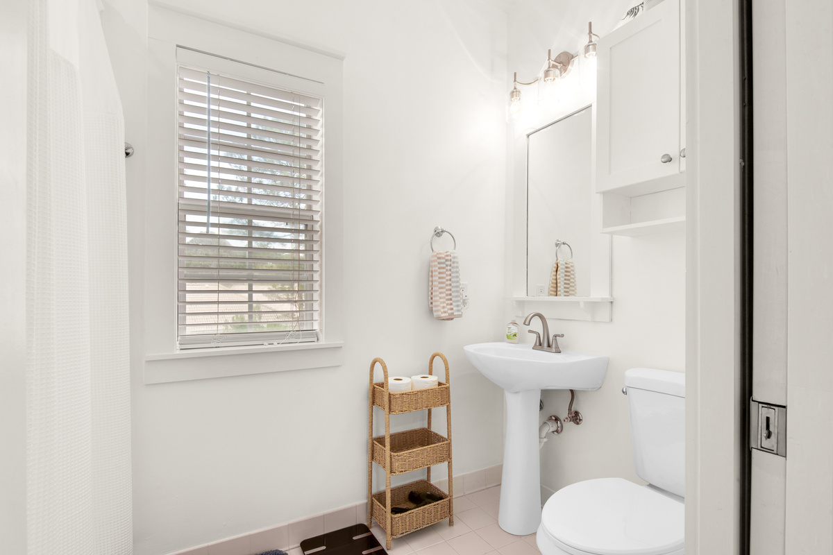 Seagrove Bungalow 103 bathroom with a pedestal sink, mirror and built-in shelving.
