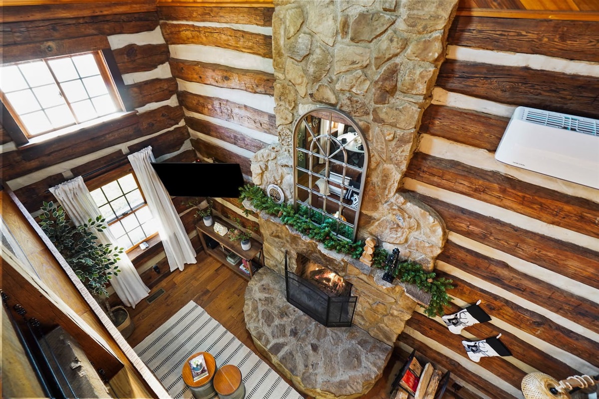 Gorgeous view of an open area below, with a stone fireplace adorned with a mirror.