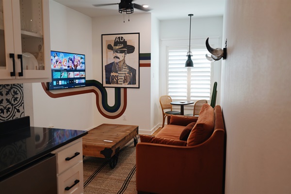 Stylish living space featuring custom wall art, natural light, and a compact dining area for two.