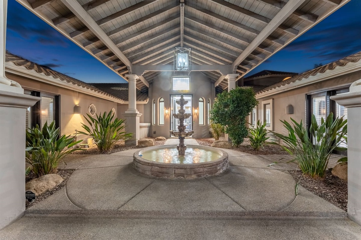 A covered walkway leads to the main entrance, centered around a peaceful fountain—setting the tone for a luxury stay.

