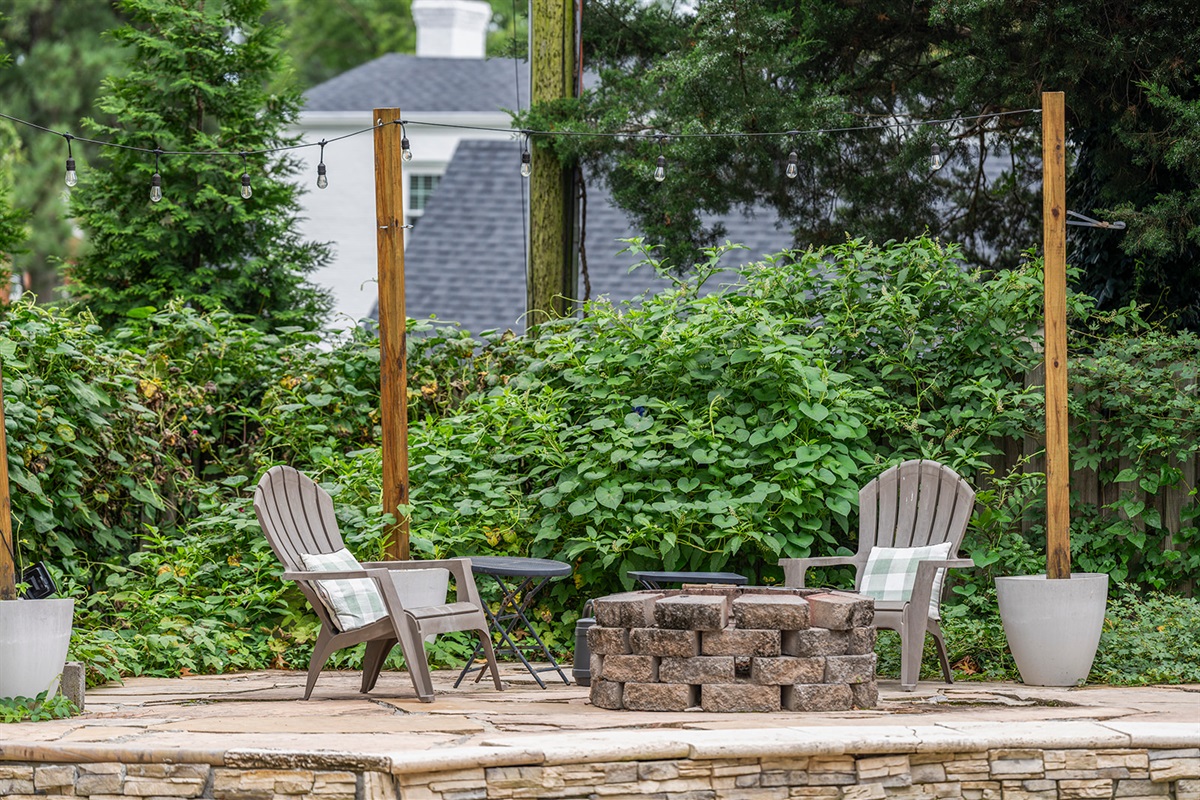 Outdoor Retreat: Unwind by the fire pit amidst lush greenery and twinkling lights!