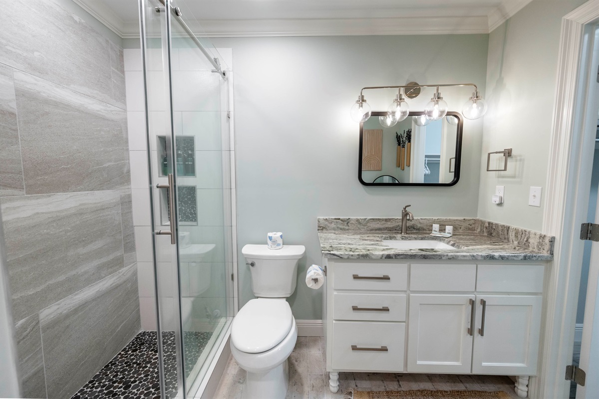 Elegant bathroom with glass shower, marble countertop, and sleek lighting for a modern look.
