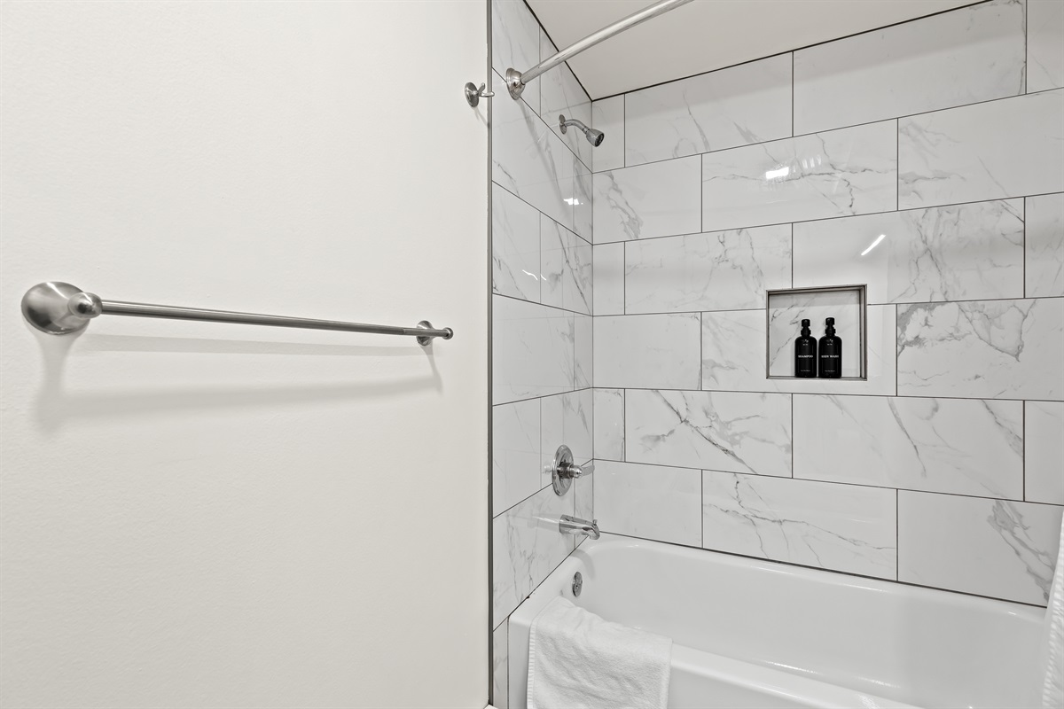 Unwind in a clean, modern shower with stylish marble-style tiles and complimentary bath essentials.