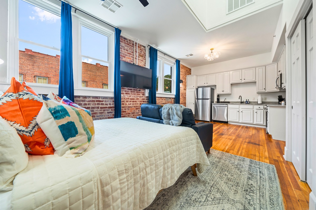 The studio’s open layout seamlessly integrates the bedroom, living, and kitchen spaces, providing style and practicality.