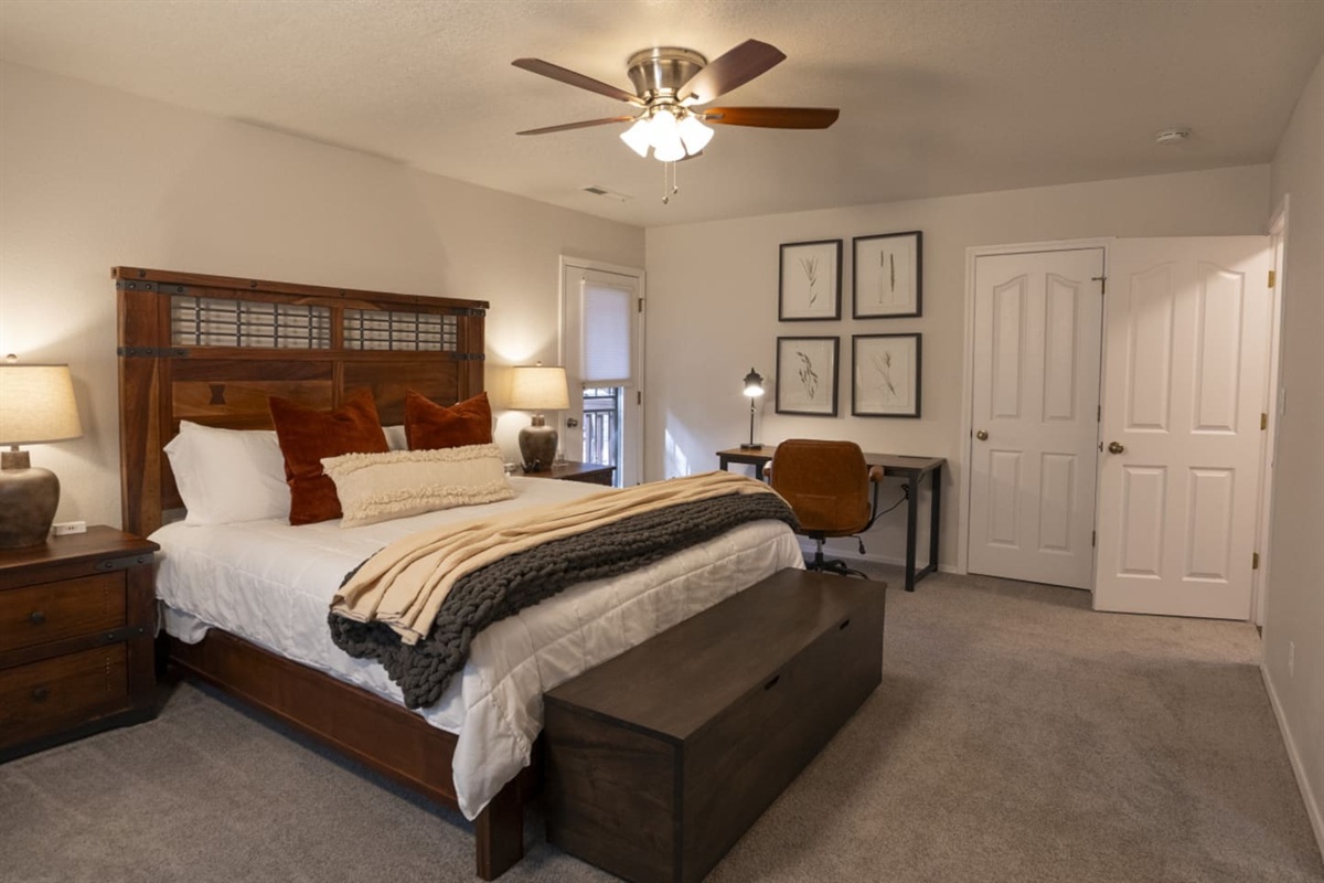 Spacious primary bedroom with a large king bed, work desk, closet storage, and comfortable seating.