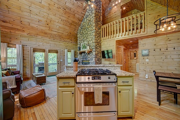 Stainless steel appliances, granite countertops, stone fireplace, and vaulted ceiling