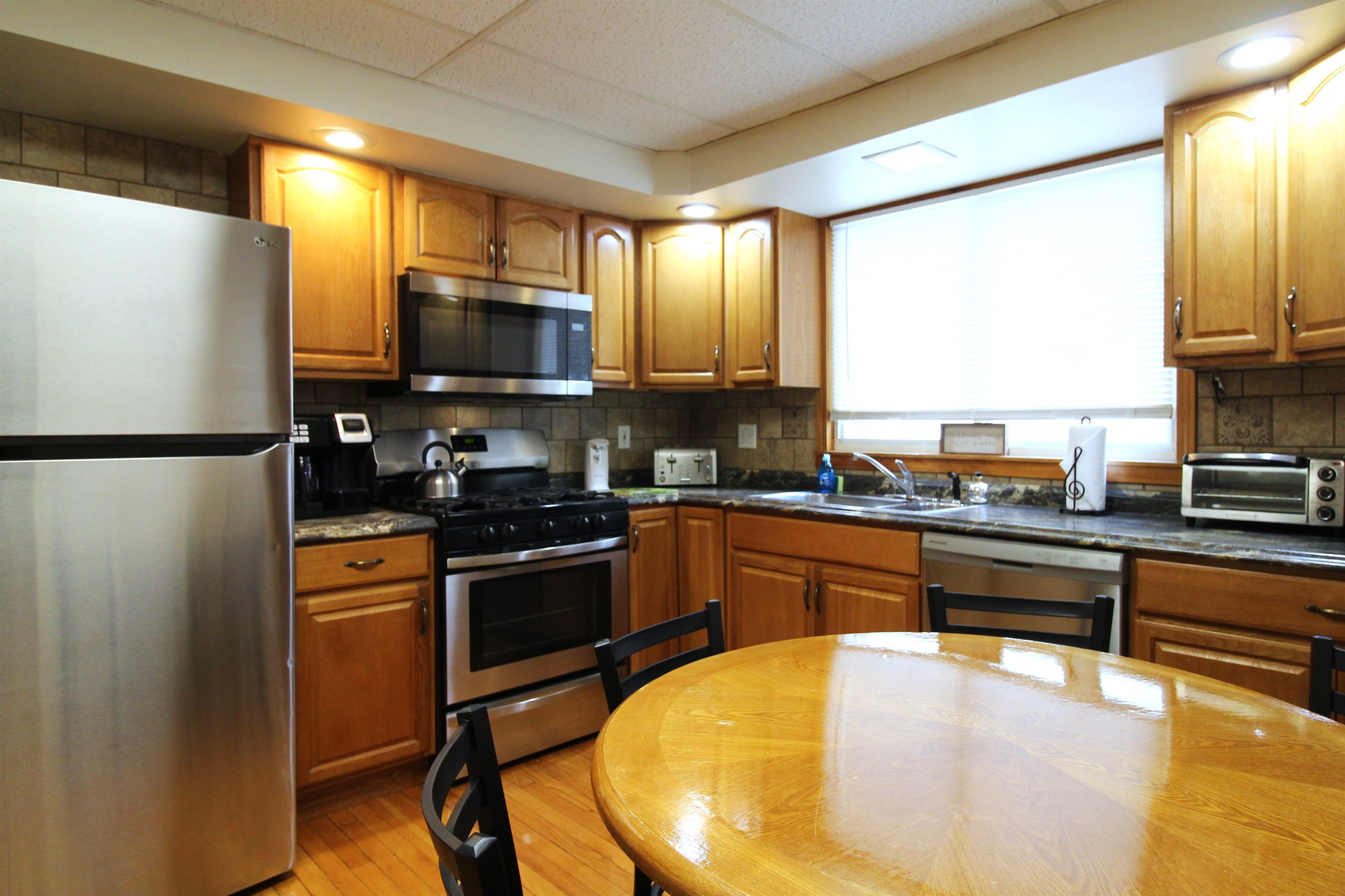 Fully equipped kitchen with hardwood floors and tiled backsplash.  Features a gas range, microwave, dishwasher, and full size refrigerator with automatic ice maker.