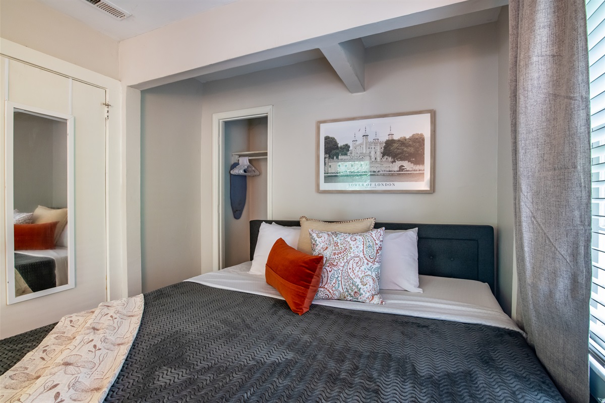 Charming guest room with bold accent pillows, mirrored closet, and modern touches.