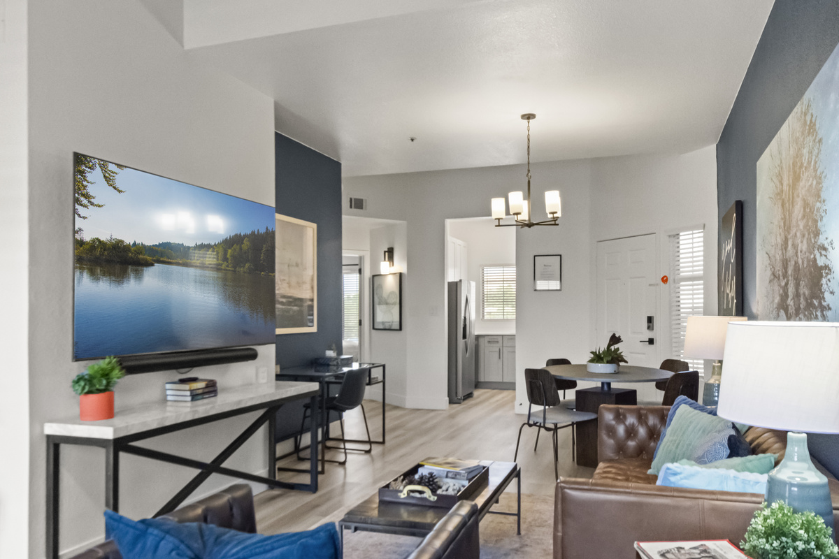 Bright and inviting living room with comfortable seating, a large TV, dining area, and modern décor.
