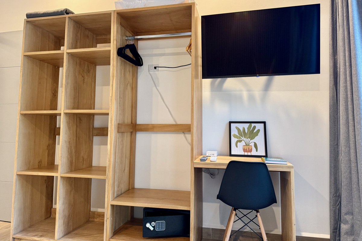 Master suite — wardrobe, integrated workspace with chair, wall TV, and safe.