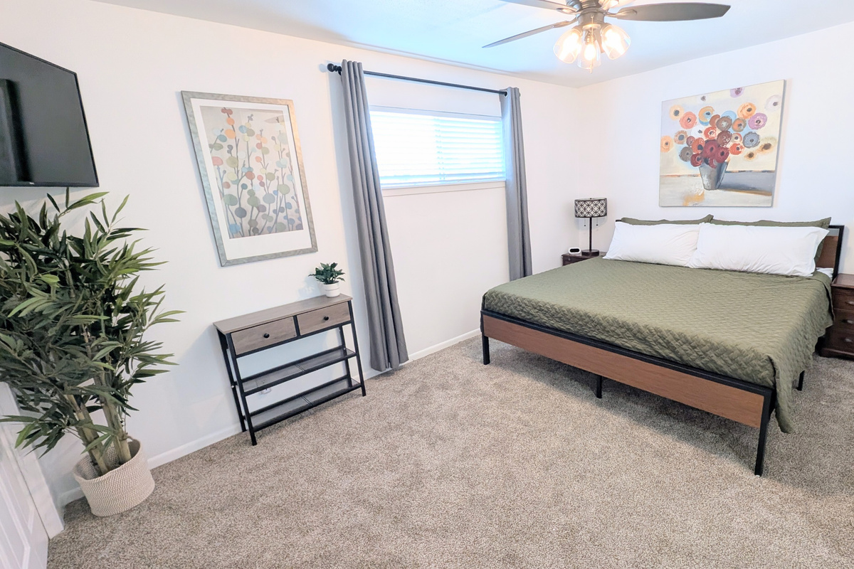 King bedroom has blackout curtains, ceiling fan, charging stations, Roku TV, closet space, and plenty of plush pillows and bedding. 