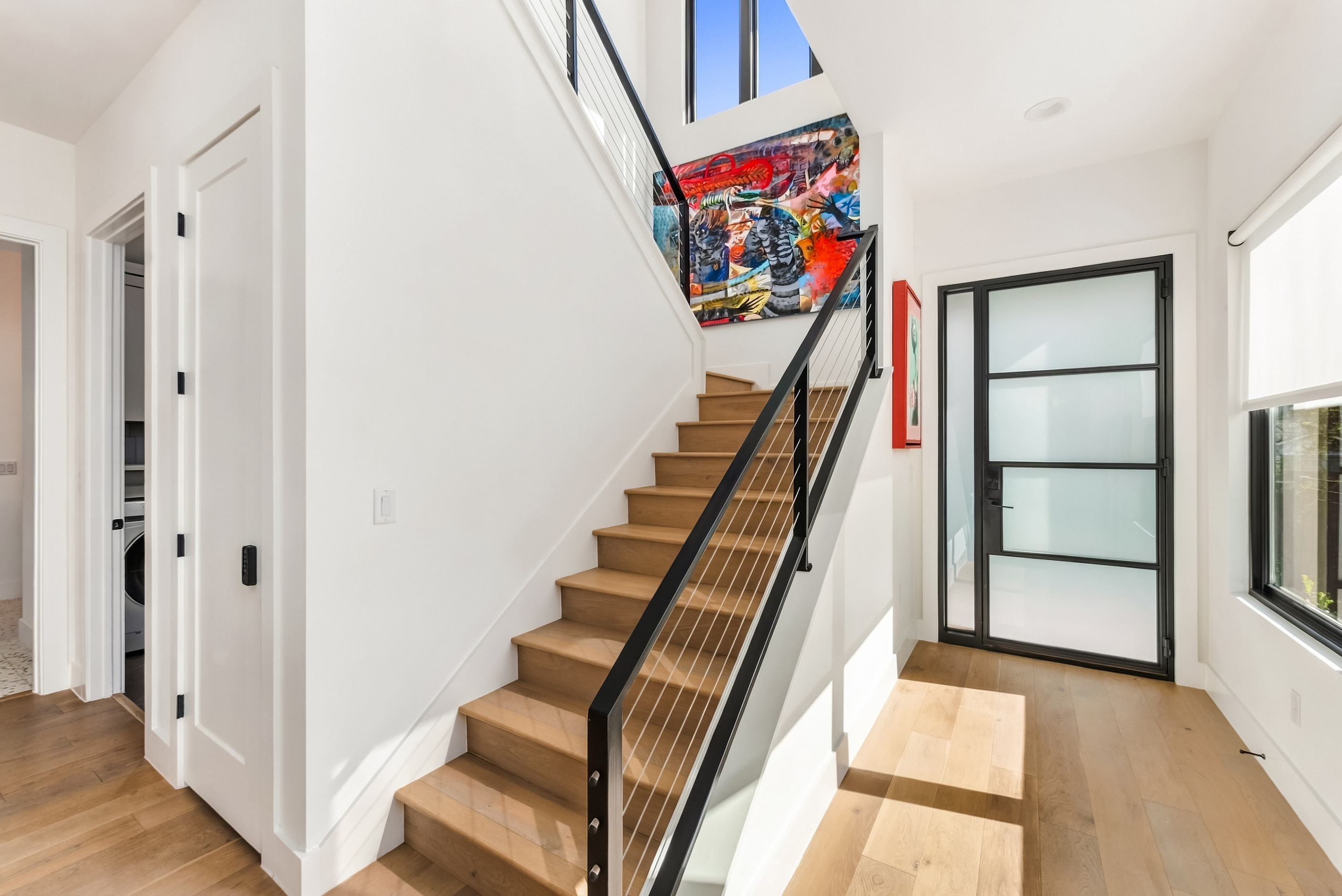 Modern black-railed staircase greets you just past the front entry