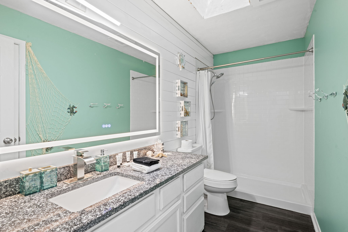 A bright, beach-inspired bathroom with granite counters, a walk-in shower, and playful nautical decor.