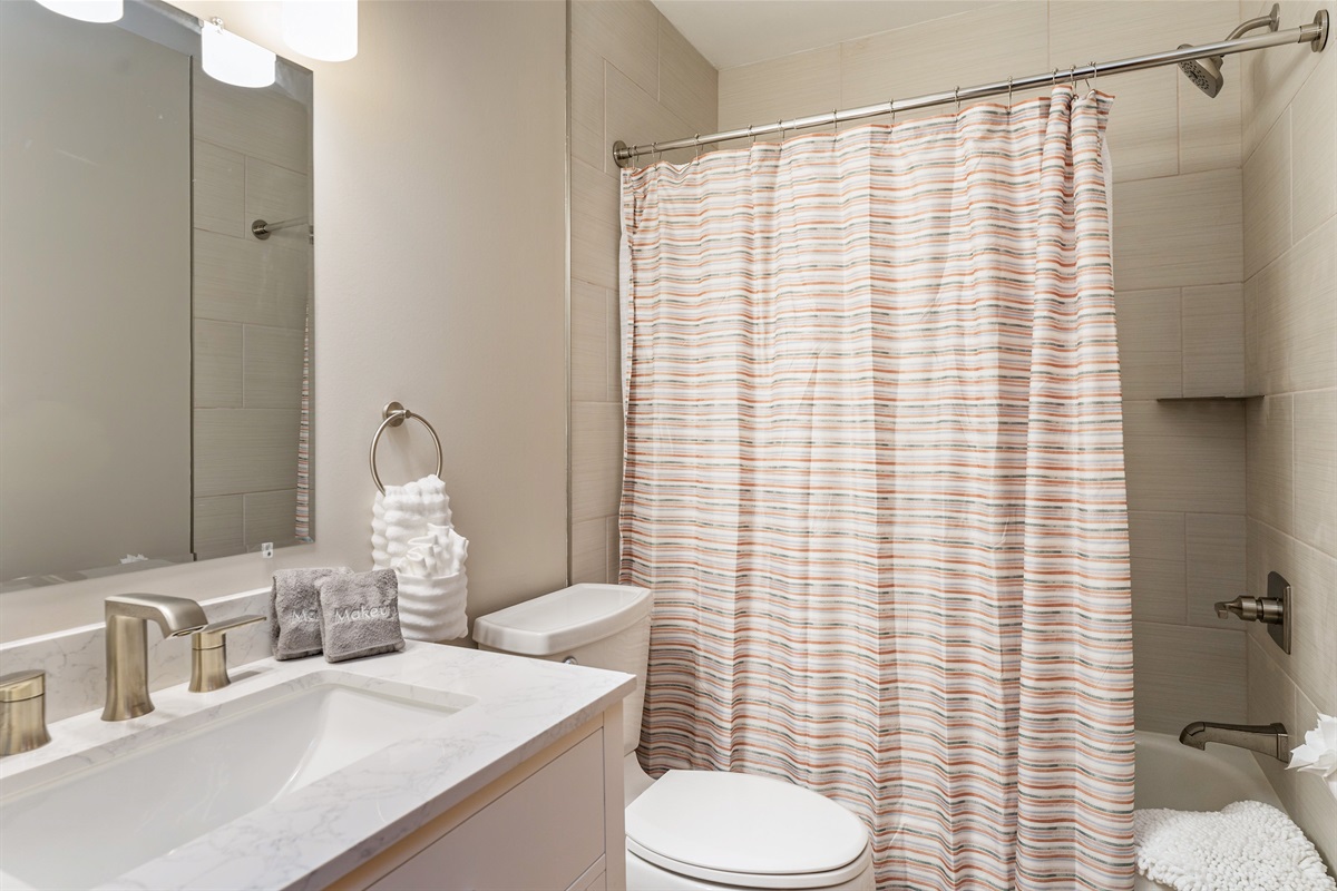 Fresh and modern bathroom with sleek fixtures, a marble vanity, and a cozy shower/tub combo—perfect for unwinding after a day of exploring.