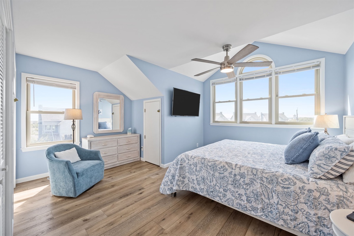 This inviting primary suite offers a plush king bed, coastal décor, ceiling fan, and plenty of space to unwind—perfect for slow mornings and peaceful nights.