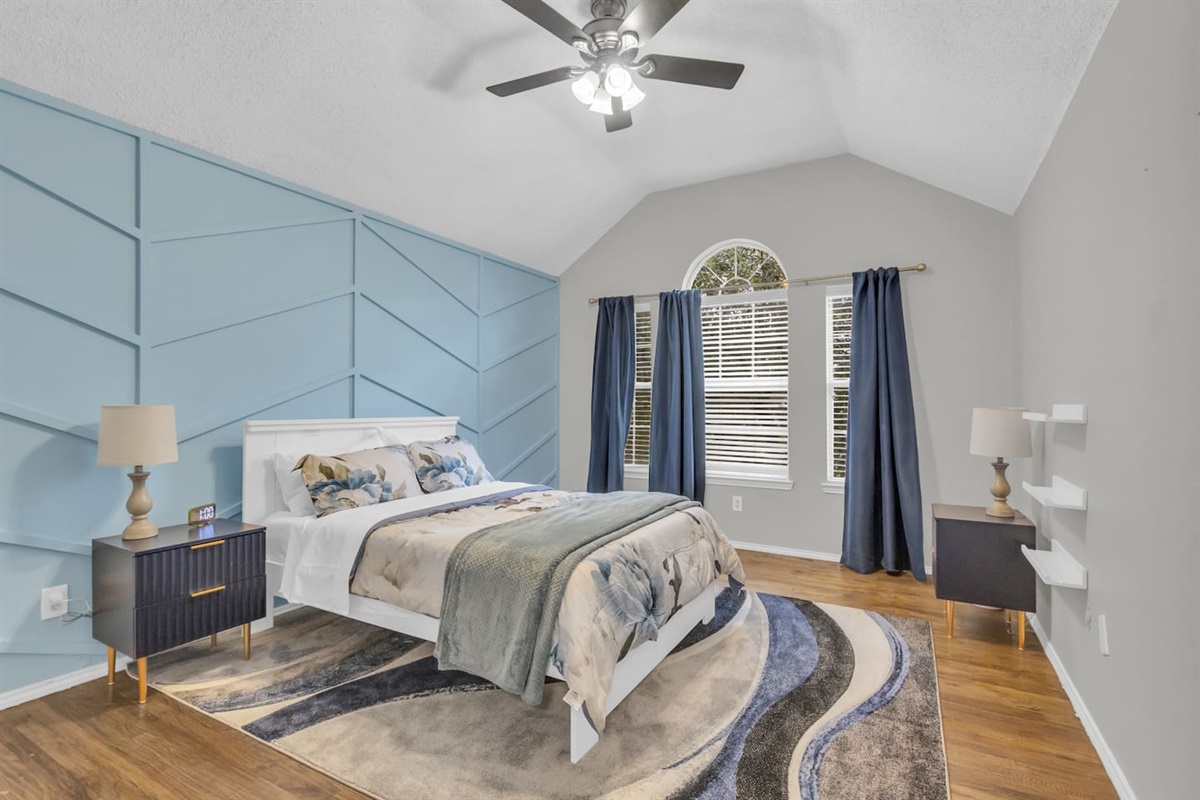 Spacious guest bedroom featuring a comfortable queen bed, room-darkening blinds, ceiling fan, fresh bed linens, hangers, and a quiet setting ideal for restful sleep.