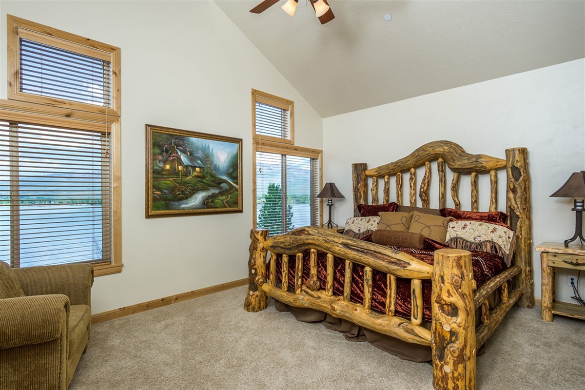 A stunning primary bedroom featuring a handcrafted log bed, vaulted ceilings, and large windows—offering both comfort and rustic luxury.
