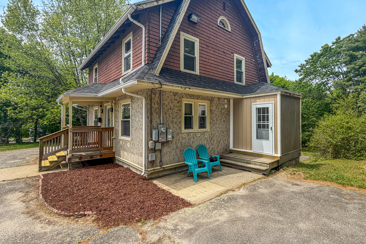 An open 3/4 view showcases how the wide driveway connects directly to your main check-in entrance. With two Adirondack chairs positioned nearby, this layout makes it easy to step straight from your vehicle into the functional mudroom drop zone.