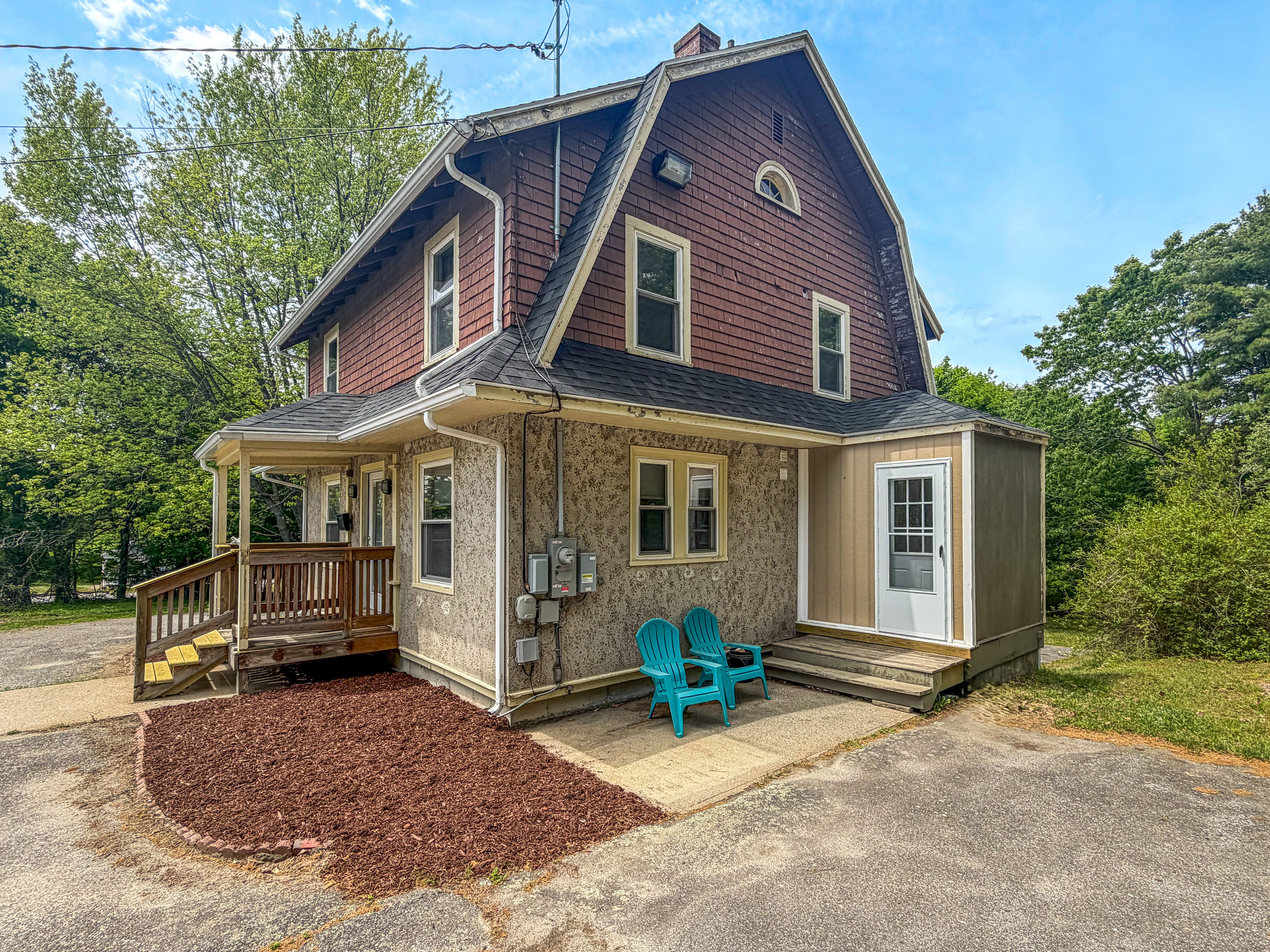 An open 3/4 view showcases how the wide driveway connects directly to your main check-in entrance. With two Adirondack chairs positioned nearby, this layout makes it easy to step straight from your vehicle into the functional mudroom drop zone.