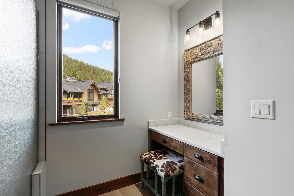 Primary bathroom with sit-down vanity and mountain view from window (blinds on window lower from the top of raise from the bottom with options to block or filter light). 
