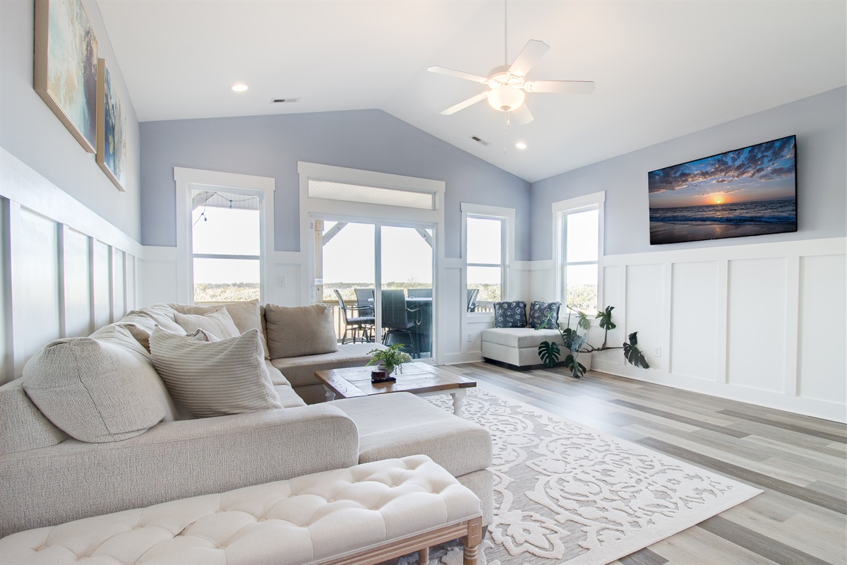 Bright, open living space with coastal style, comfy seating, and easy access to the deck for indoor-outdoor living