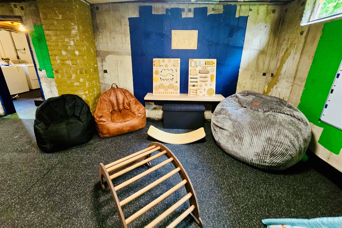 The Energy Hub is built for movement, imagination, and family connection—bean bag seating for flexible lounging, sensory boards and a balance board for active play, with the laundry room nearby to keep everyday rhythms flowing.