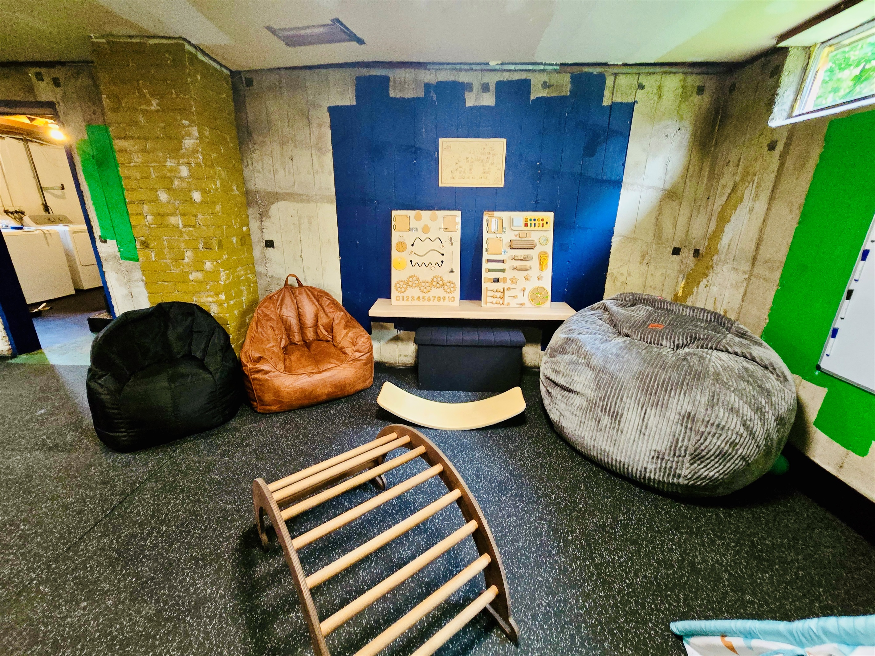 The Energy Hub is built for movement, imagination, and family connection—bean bag seating for flexible lounging, sensory boards and a balance board for active play, with the laundry room nearby to keep everyday rhythms flowing.