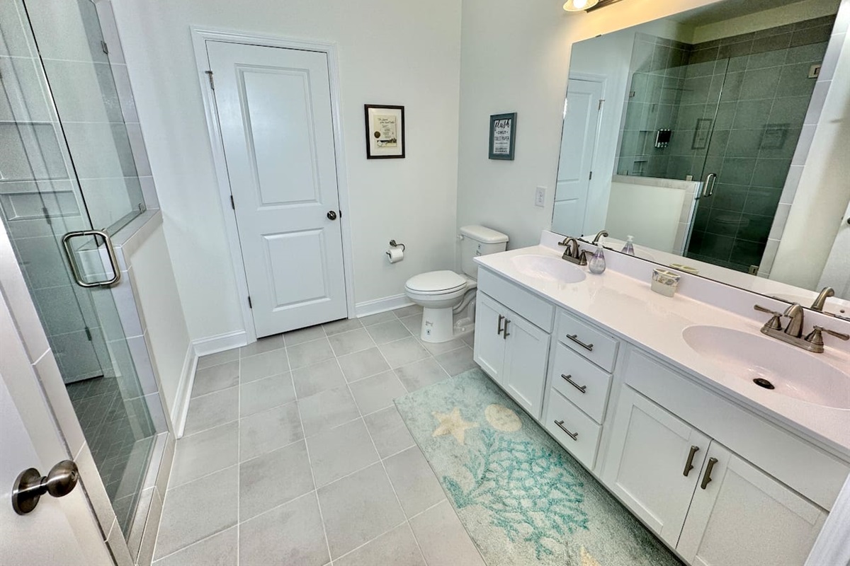 Master bathroom has a ceiling-to-floor tile shower with glass enclosure and 2 sinks.