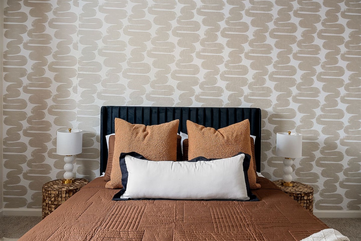 Admire the elegant design of this bedroom, featuring a plush headboard and modern bedside lamps. Perfect for a comfortable and stylish retreat.