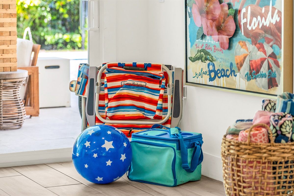 This cheerful coastal corner is thoughtfully stocked with beach essentials, ready for a day of sun and relaxation.  Bright artwork and natural textures create a welcoming vibe that perfectly complements this luxury Airbnb's laid-back seaside style.
