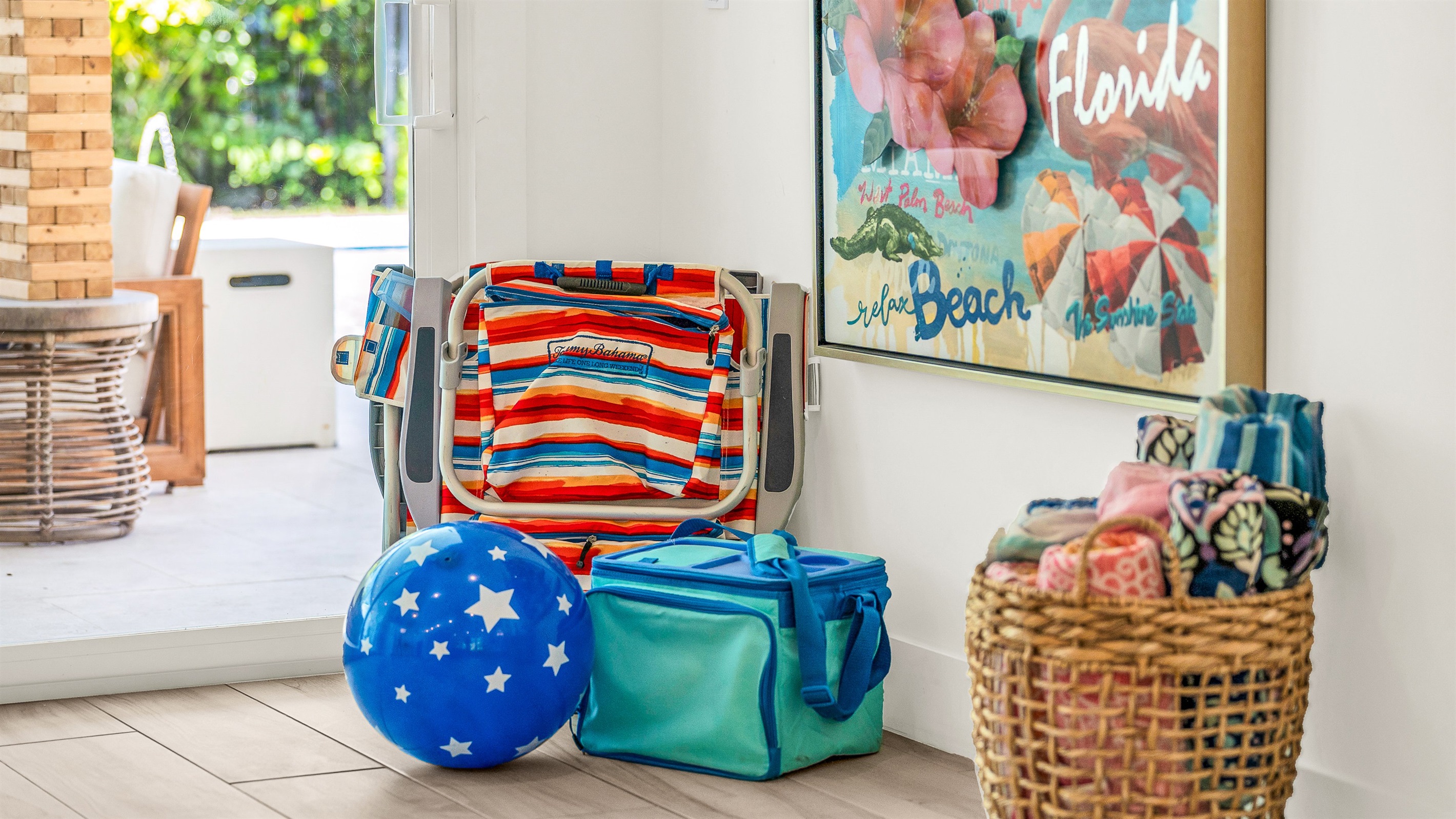 This cheerful coastal corner is thoughtfully stocked with beach essentials, ready for a day of sun and relaxation.  Bright artwork and natural textures create a welcoming vibe that perfectly complements this luxury Airbnb's laid-back seaside style.