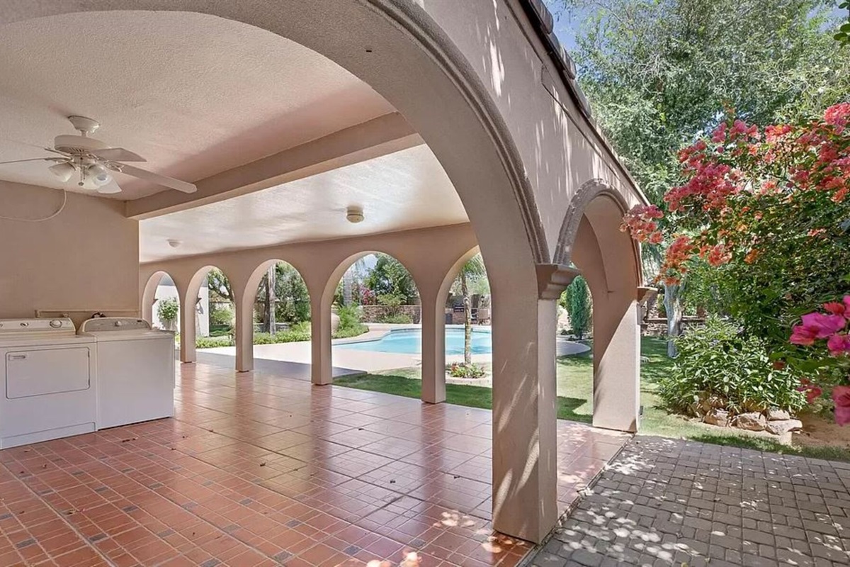 Lounge beneath graceful arches with views of the sparkling pool and blooming desert flowers in this serene outdoor living space.