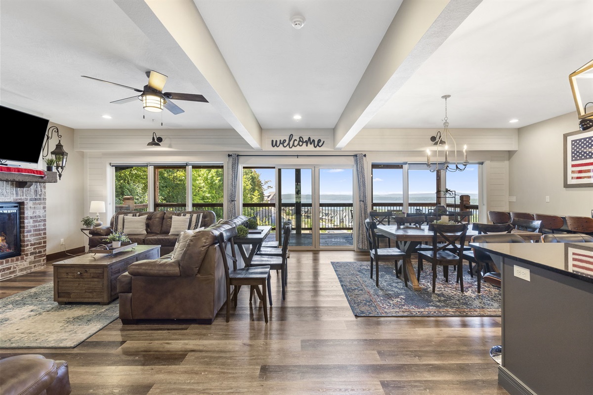 Main level living room with large TV and fireplace. Open dining and kitchen area.