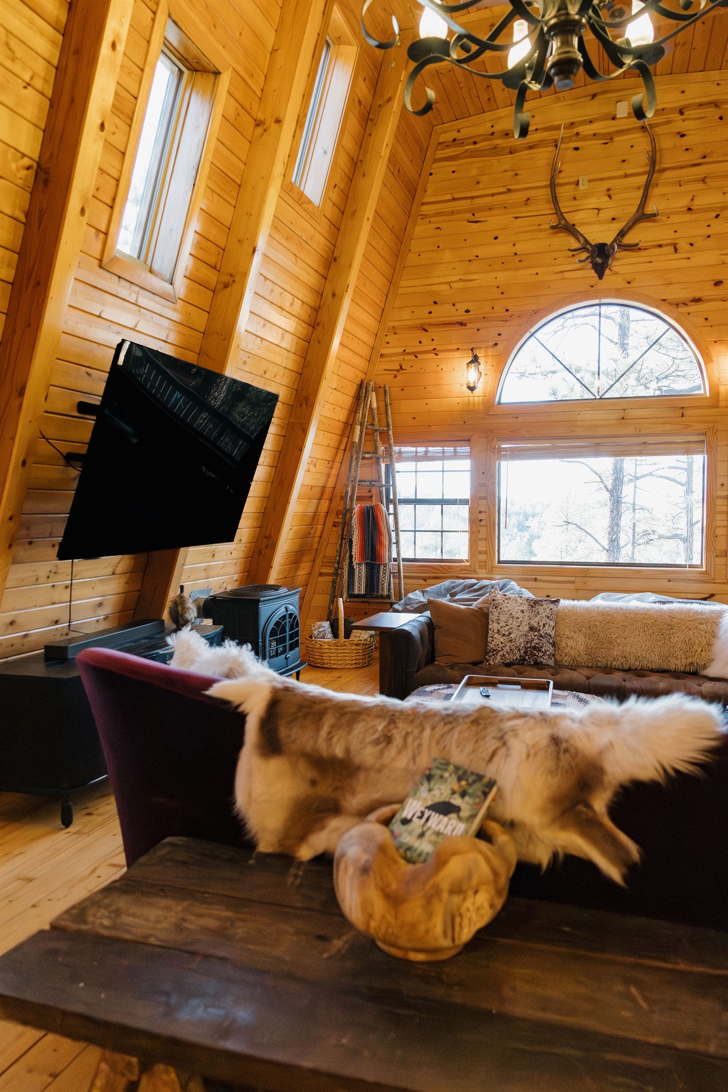 Dramatic A-frame architecture floods Poppywood Pines with natural light from soaring windows. This unique gothic western Show Low cabin features cozy furnishings and authentic decor, creating your perfect White Mountains retreat near hiking, fishing, and s