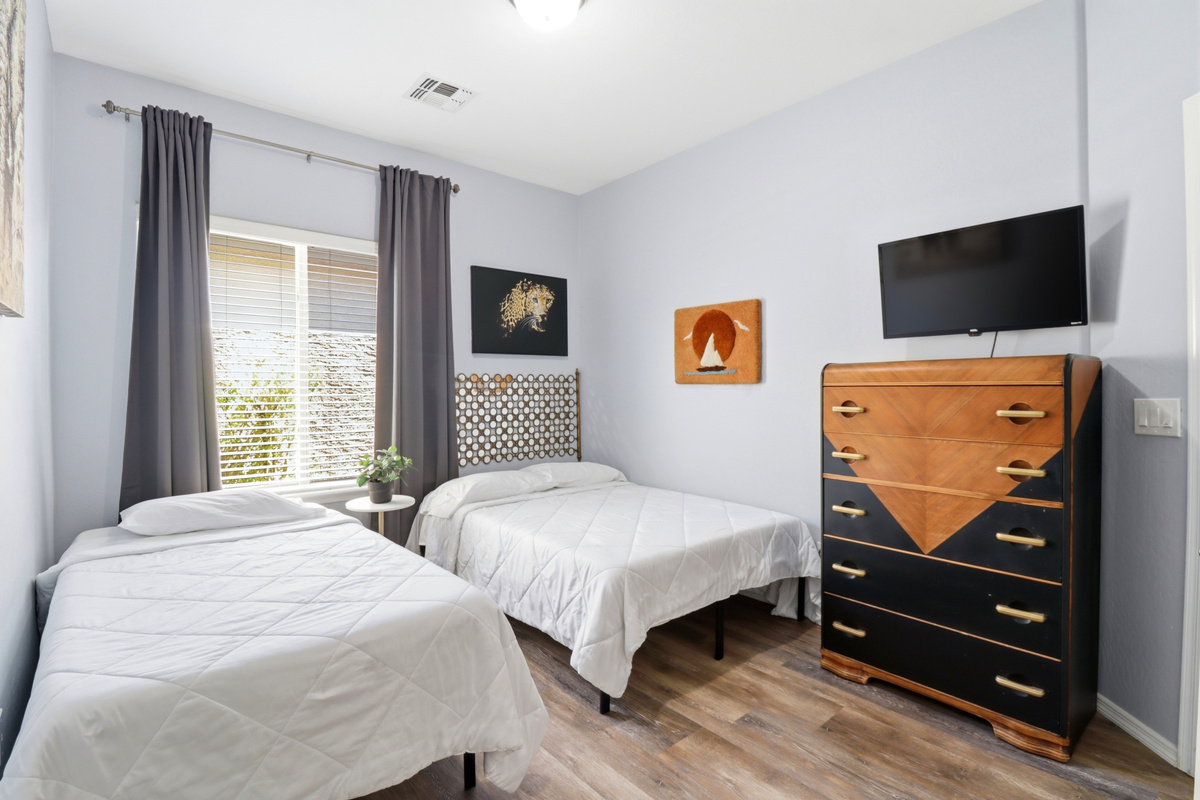 Bedroom with one twin bed, one full bed, dresser storage, and a TV.
