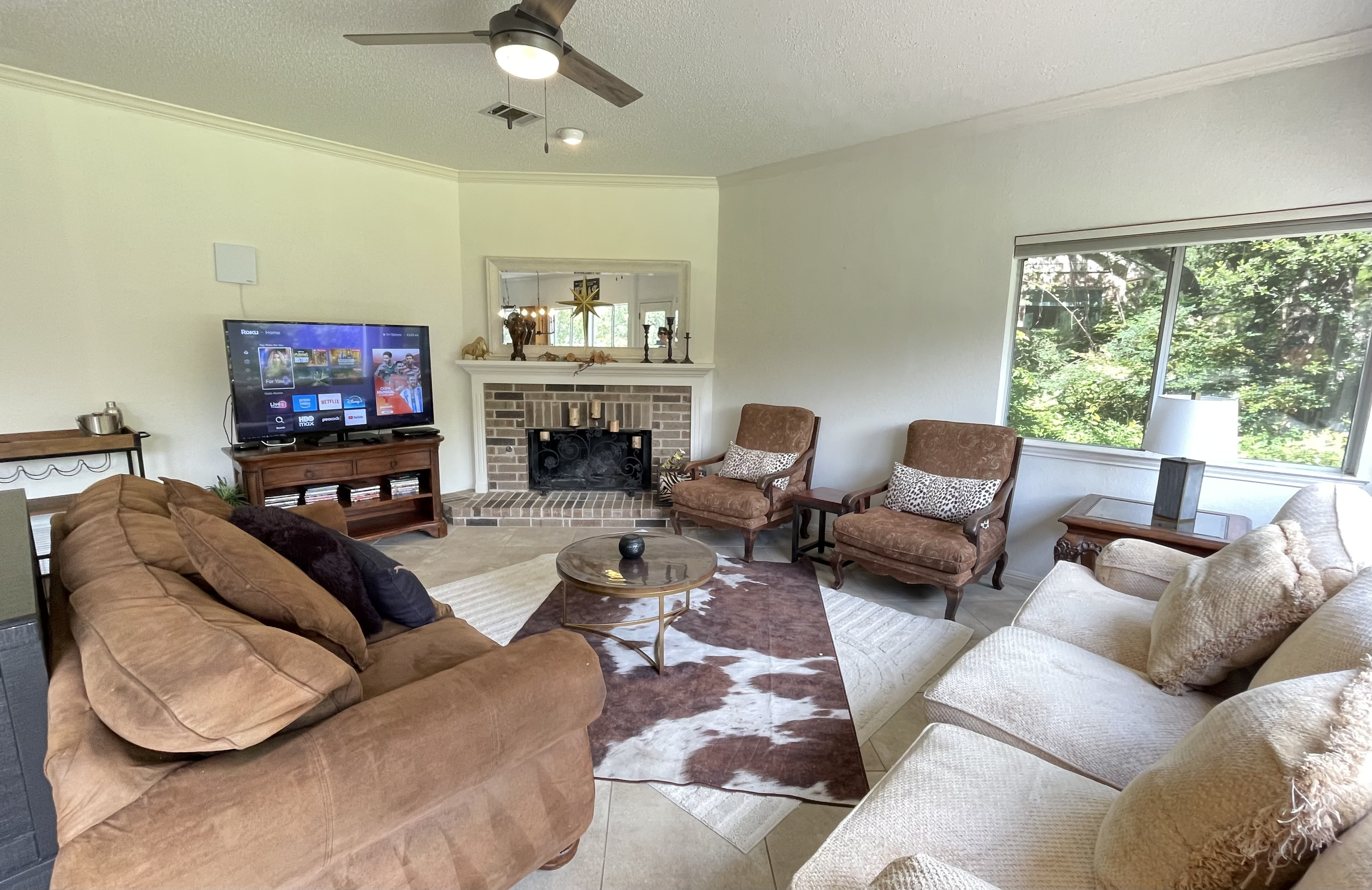 This stylish living space features generous seating,  an entertainment center that includes a 65-inch LED TV,  Roku and Apple TV for streaming, antenna for live TV, DVD player and DVDS, a beverage cart.