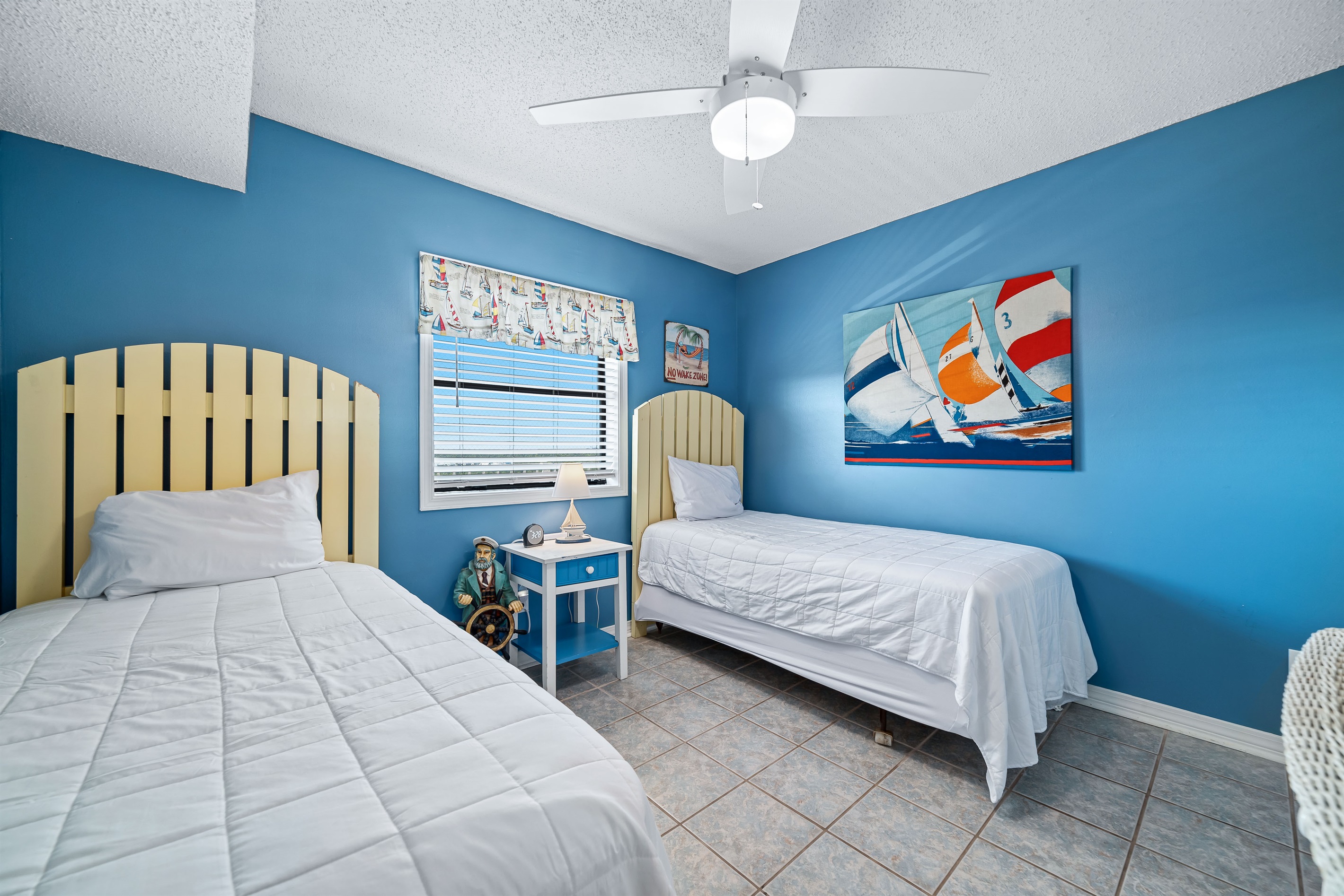 Coastal-inspired guest room with two twin beds, featuring light and airy decor and a glimpse of the surrounding scenery.