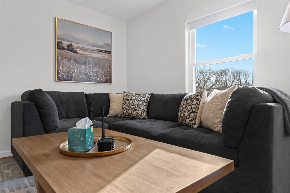 Stretch out on a plush sectional surrounded by natural light, cozy textures, and calming décor—perfect for relaxing after a day exploring the area.