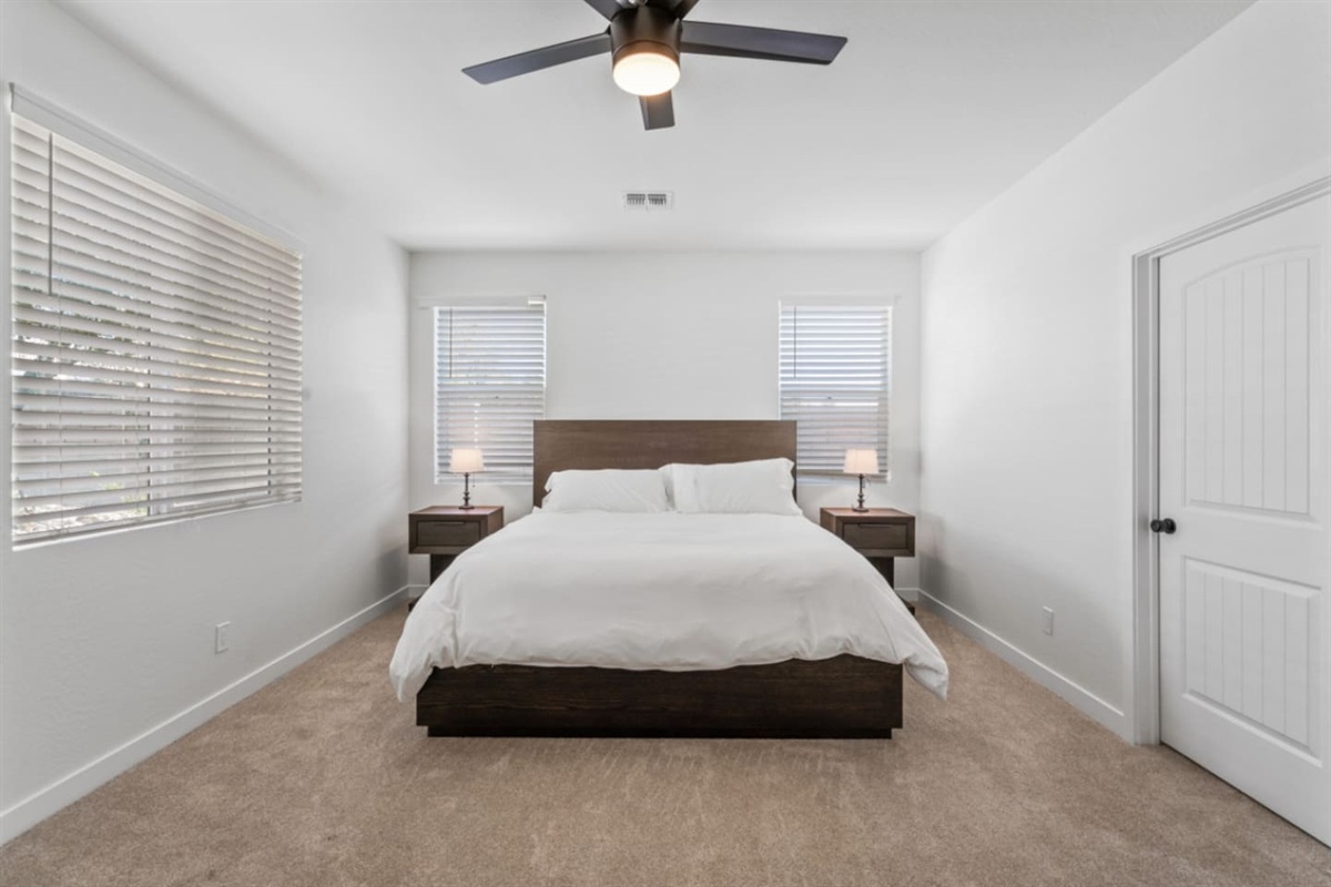 Master bedroom with ensuite bathroom access, large bed, ceiling fan, and a clean, spacious layout for a restful stay.