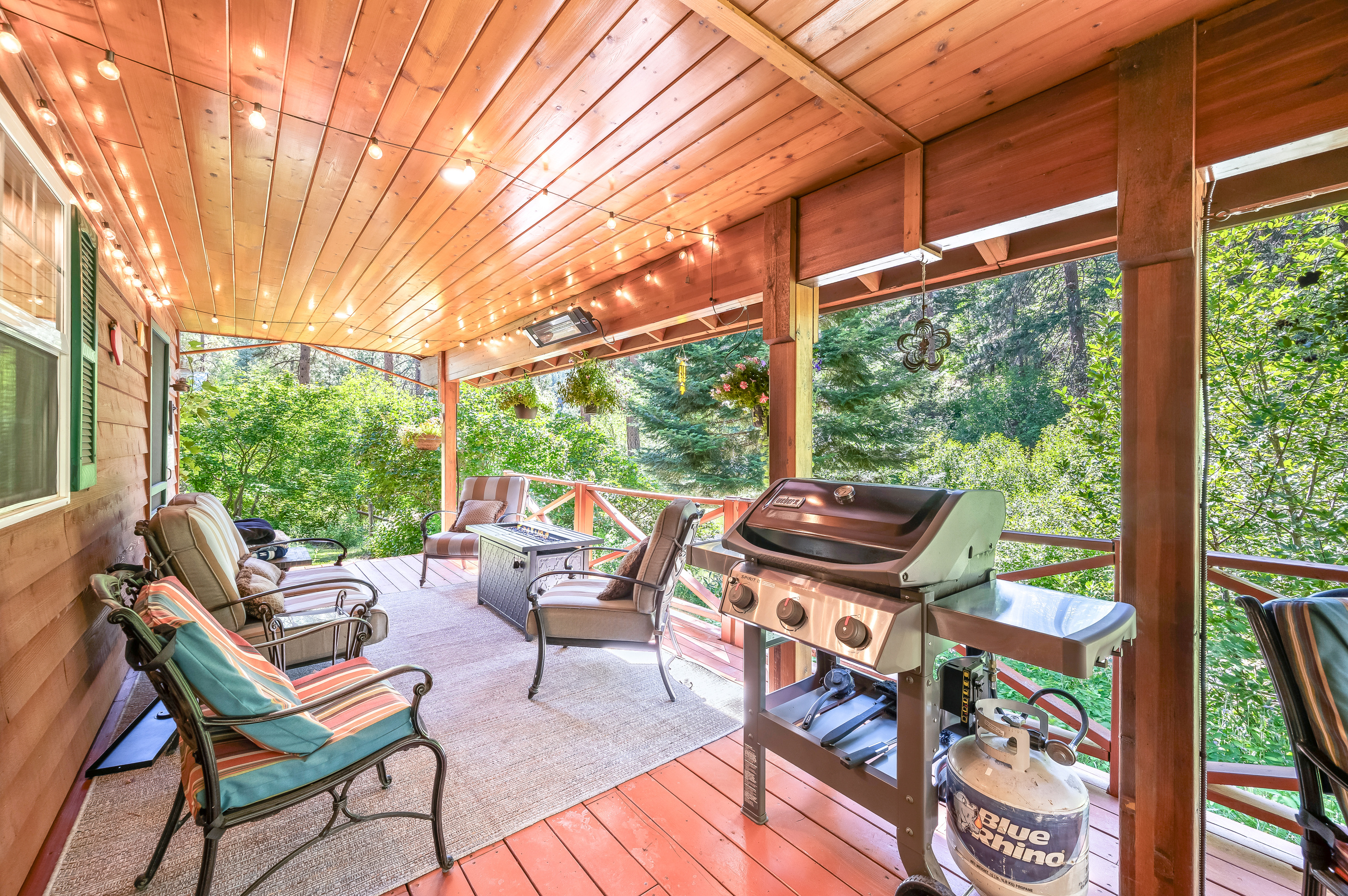 Large covered back porch includes gas BBQ (propane provided), seating area, and fire table