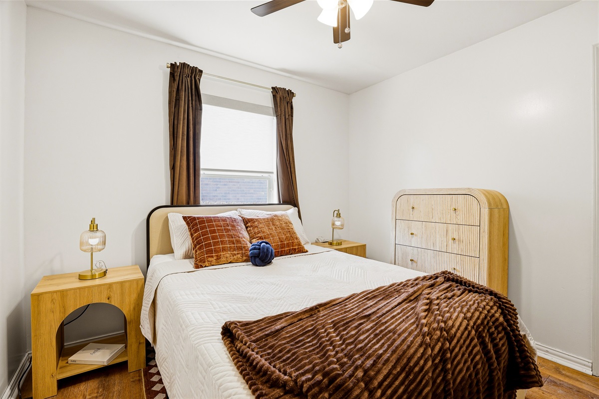 Comfortable double bedroom with plush bedding, chest of drawers, ceiling fan, and room-darkening shades. Closet and nightstands included — everything set up for a restful night's sleep.
