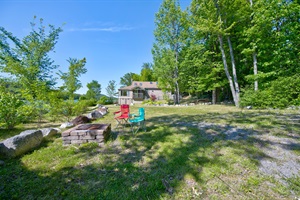 brick firepit and chairs with the property in the background