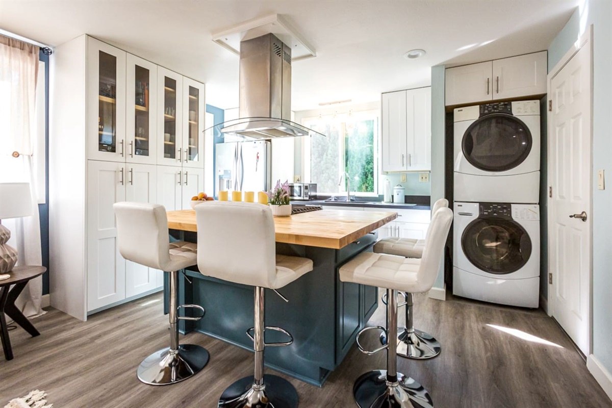 - Modern kitchen with spacious wood island, four chic bar stools, & built in gas cooktop  
- Crisp white cabinetry pairs with stainless steel appliances for a clean, stylish vibe  
- Stacked washer & dryer seamlessly integrated for convenience  
