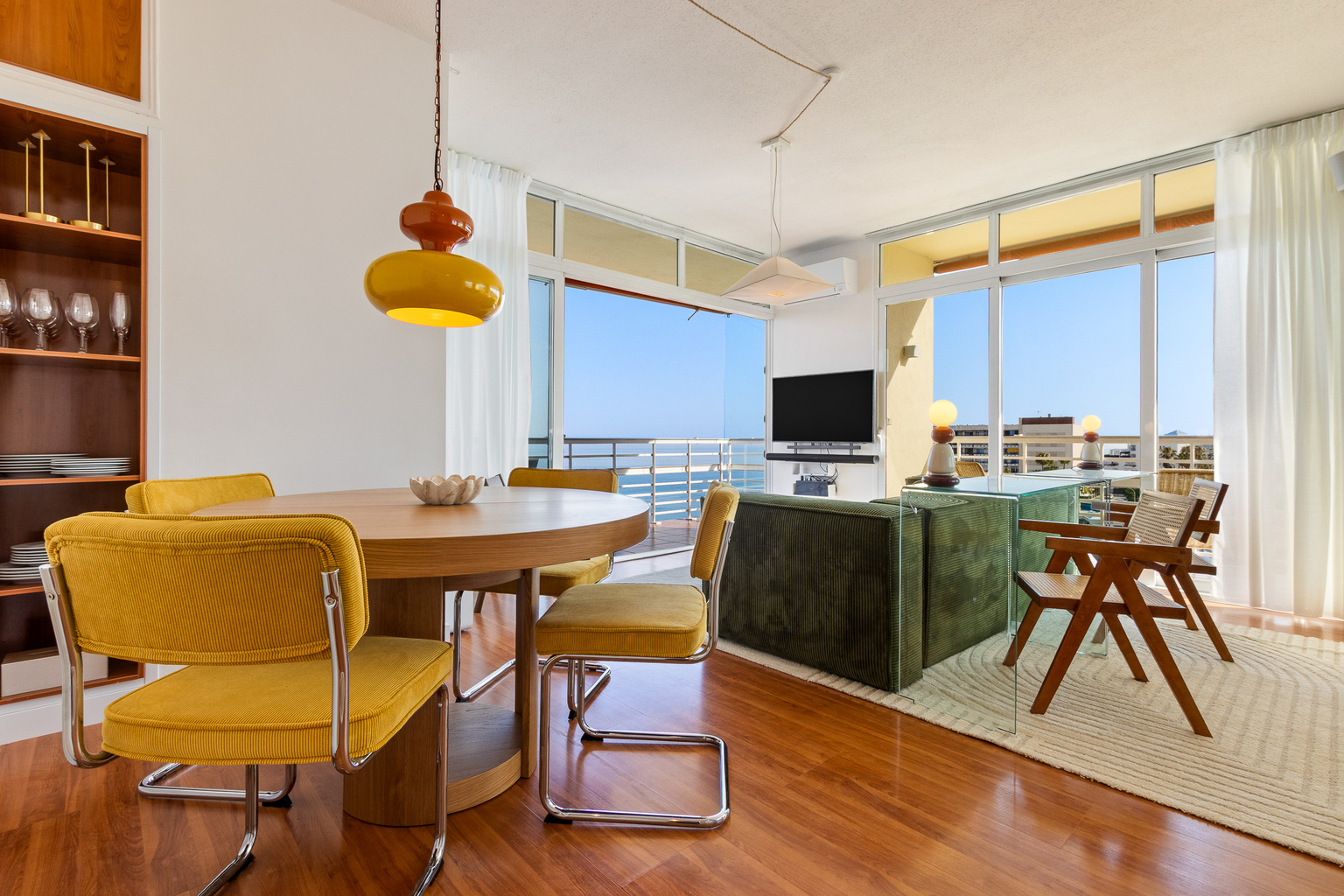 Bright open-plan living and dining area with sea views and balcony access.