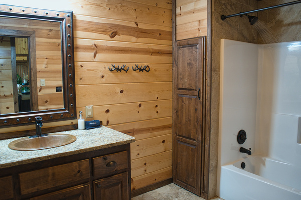 Hall full bath with a bathtub/shower combo, conveniently located between the guest king bedroom and the queen/bunk room — an easy shared bathroom setup for families or groups staying at Sierra Sky.