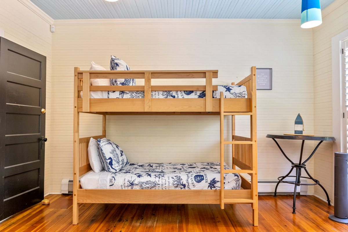 Bunking down under the classic beadboard ceilings. This angle of the "Crew’s Quarters" shows the twin-over-twin setup with matching nautical linens, giving everyone a perfect view of the new Roku TV after a long day at sea.