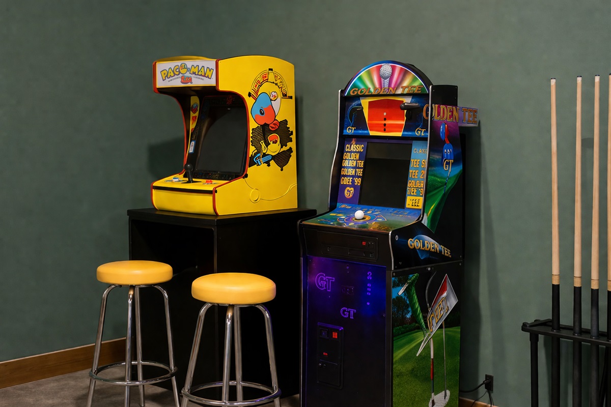 Step into a retro gaming corner featuring classic Pac-Man and Golden Tee. Enjoy endless fun right at home - perfect for a little friendly competition or a laid-back game night.