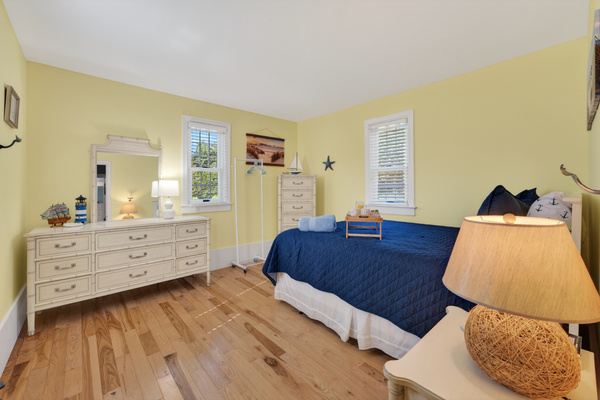 Comfortable guest bedroom with classic furnishings, hardwood floors, and a relaxing coastal feel.