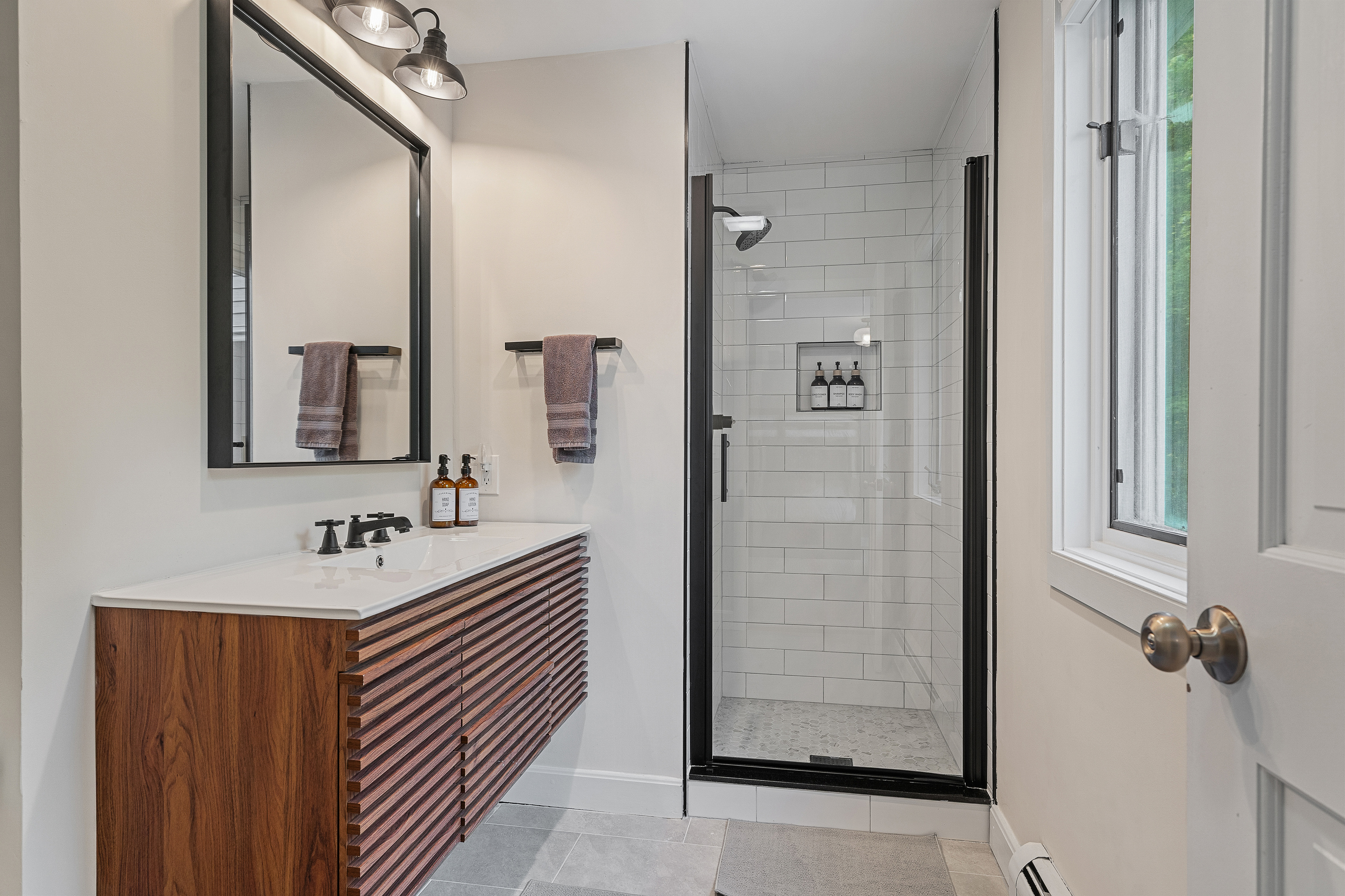 Bathroom with walk-in glass shower and double wood vanity