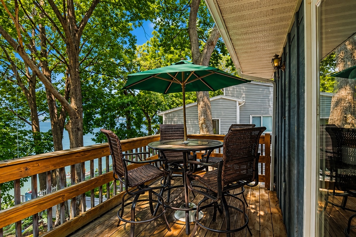 Enjoy meals or drinks outdoors on this charming deck overlooking the lake, complete with comfortable seating and a large umbrella for shade. ️